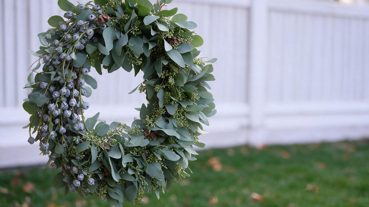 Artificial eucalyptus and berry greenery arranged as a full arch against a light background